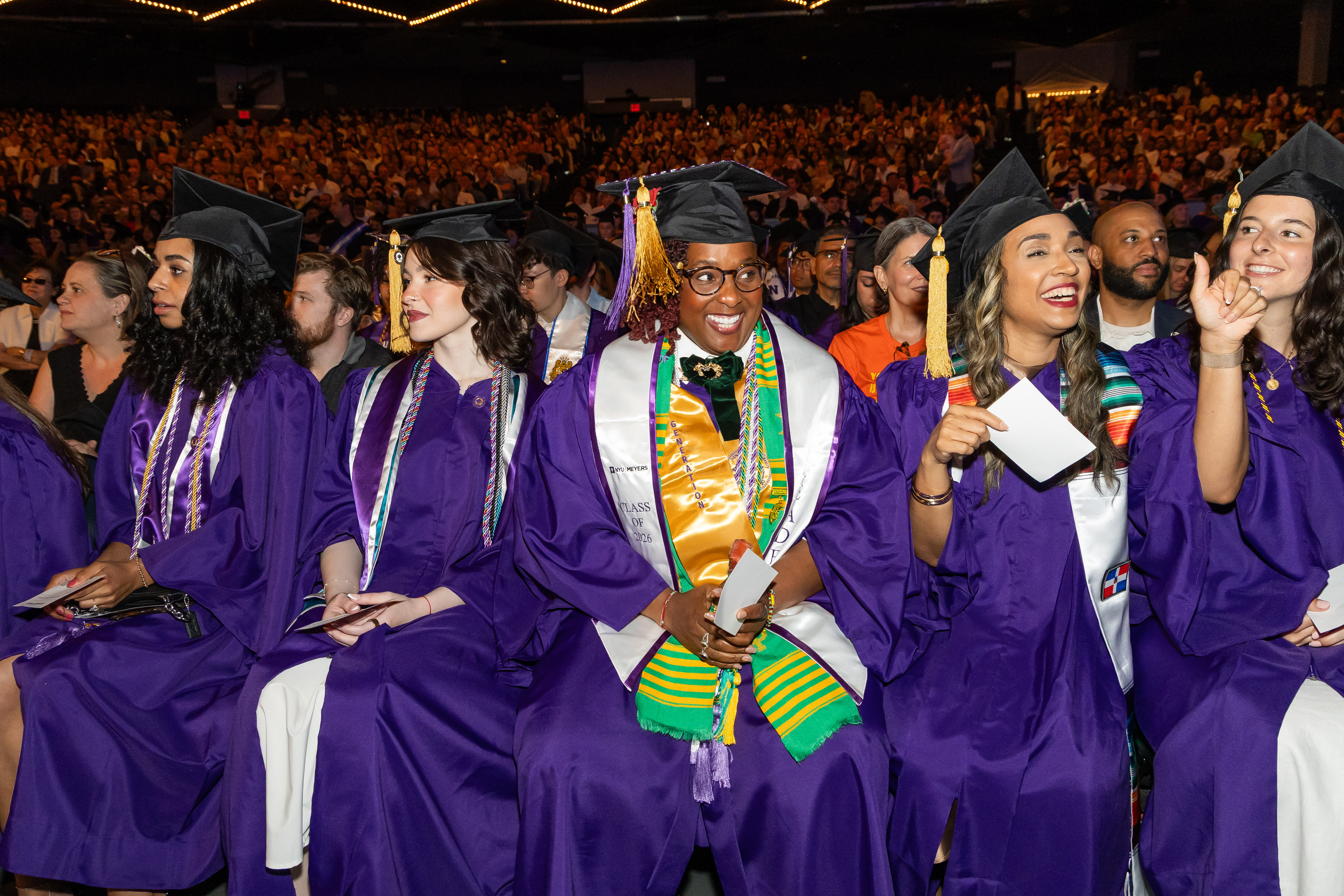 Jasmin sitting in the middle of the row with other graduates smiling 