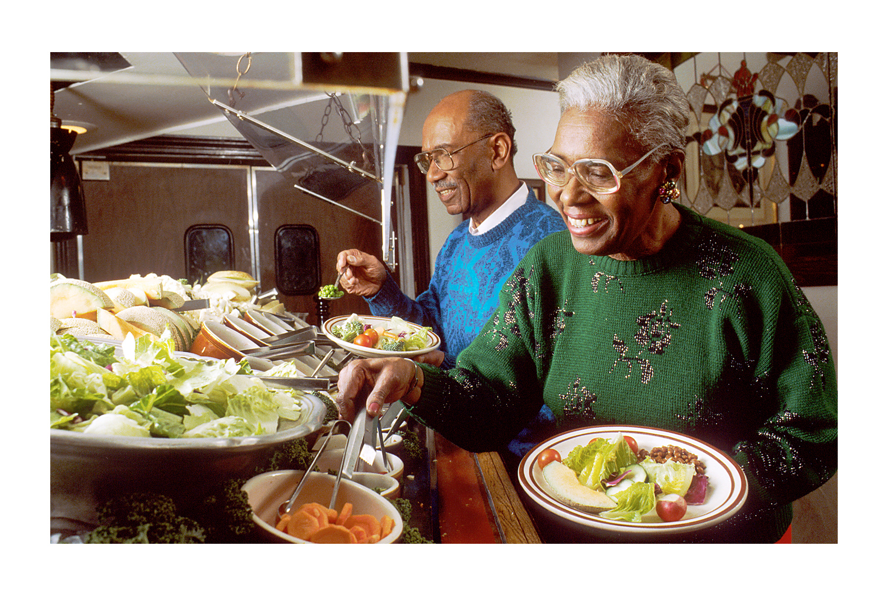 Two people eating at a salad bar