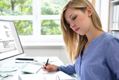 Female working at desk reviewing papers next to computer