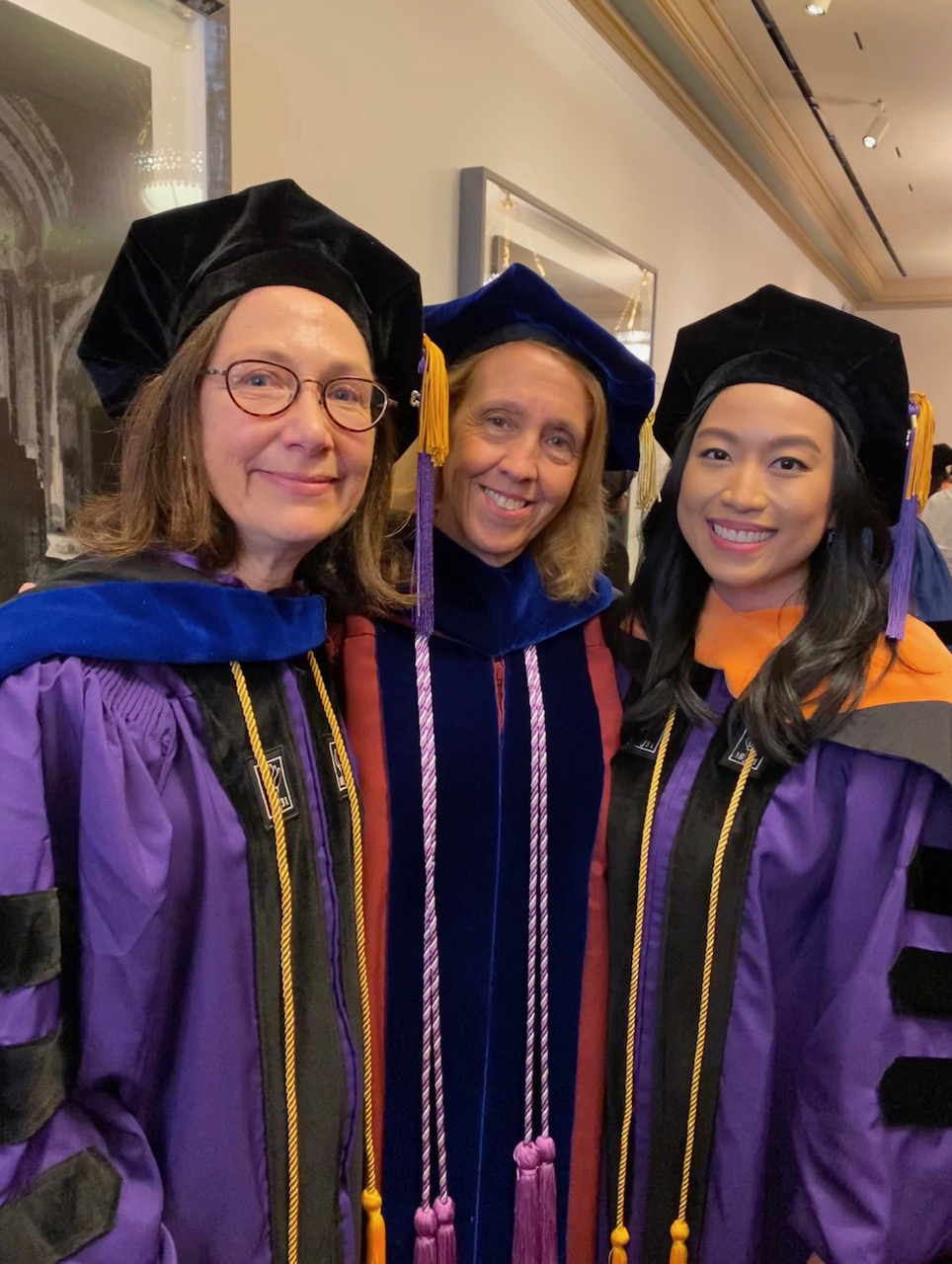 Prof. Dickson with two PhD students in graduation attire. 