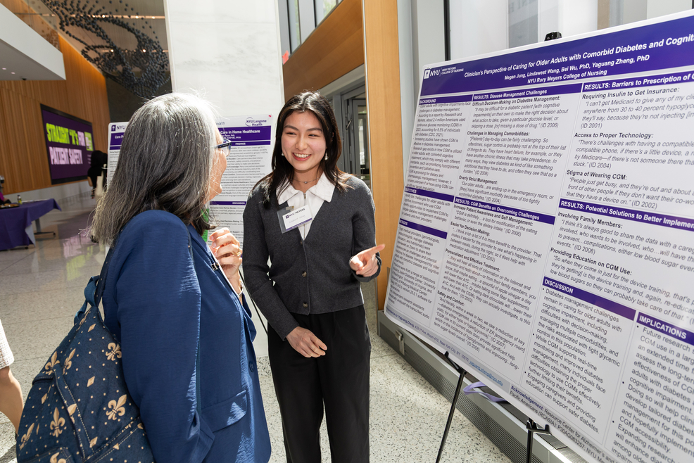 young women presenting research poster to faculty