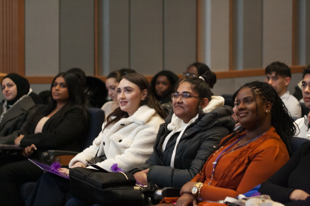 row of students in an auditorium sitting, looking and listening