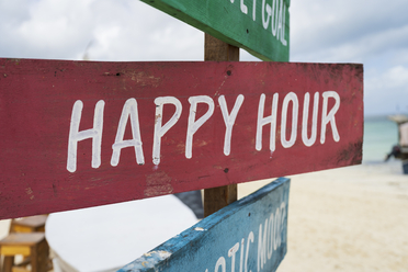 Red beach sign that says happy hour