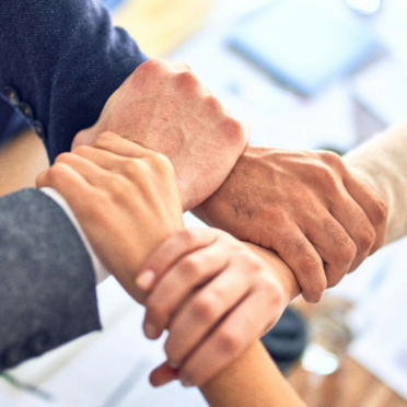 Four hands crossed over each other holding the next person's wrist