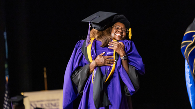 A Graduate hugging faculty member at graduation crossing stage