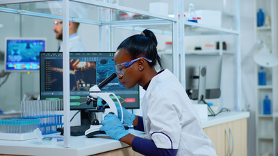 Nursing student looking through microscope in a lab